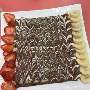 a chocolate covered dessert with bananas and strawberries