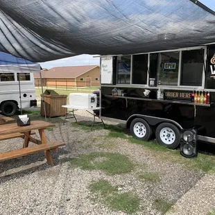 a black food truck parked next to a picnic table