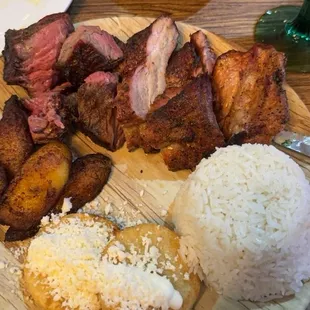 Mixed Plate (Beef and Pork Ribs) with white rice, arepitas, and Sweet Plantain; in the back Chicharrón Ceviche