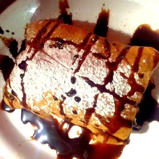 Sopapilla dessert with vanilla ice cream inside, drizzled with chocolate and cinnamon sugar. Served with jar of honey.