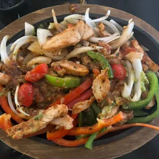 Chicken fajita with sautéed squash and a variety of veggies on a bed of lettuce.