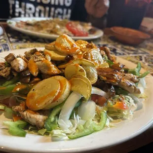 Chicken fajita with sautéed squash and a variety of veggies on a bed of lettuce.