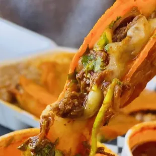 a person dipping a hot dog into a bowl of soup