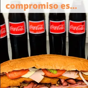 a sub sandwich with coca colas in the background