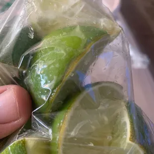 a person holding a bag of limes