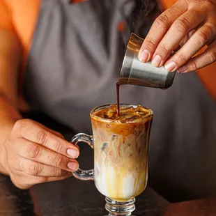 a woman pouring coffee into a cup
