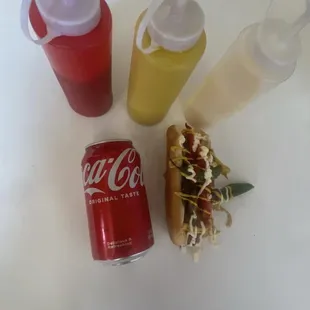 a can of coca, a hot dog, and condiments