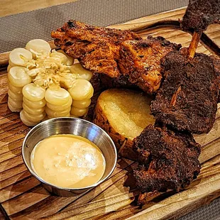 Beef heart and chicken skewers, with potato, corn (choclo), and spicy sauce. It&apos;s an appetizer, but as big as a dinner plate!