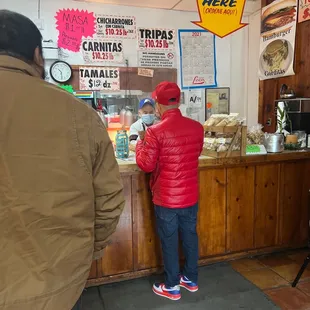 a man in a red jacket standing at a counter