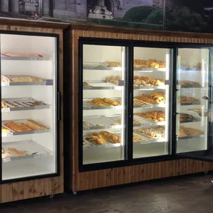 a woman standing in front of a display case of baked goods