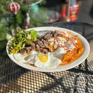 Our signature breakfast dish, the chilaquiles come with 2 eggs, salad, optional choice of meat, and topped off with queso fresco, &amp; crema