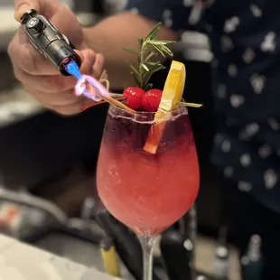 a person using a lighter to make a drink