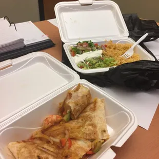 Shrimp tacos with onions and peppers in one container. In the far container Mexican rice with their signature salad mix.