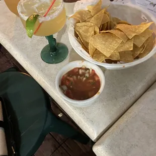a table with chips, salsa, and a drink
