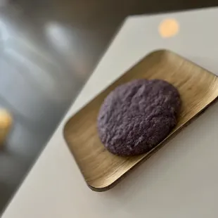a purple cookie on a wooden plate