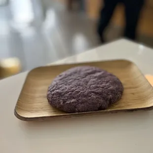 a purple cookie on a wooden plate