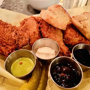 Half fried chicken with biscuits, pickles, green harissa, oyster aioli, and jams