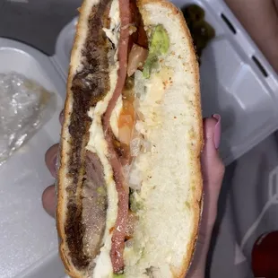 Torta cubana. Avocado, tomato, hot link, Oxacan cheese, and hand breaded beef steak.