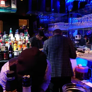 people at a bar with bottles of alcohol