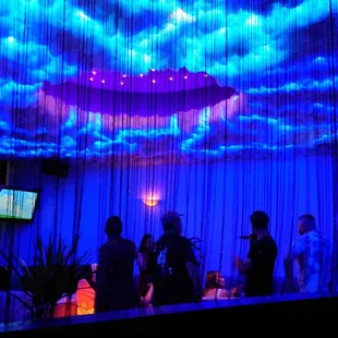 a group of people standing in front of a projection of clouds
