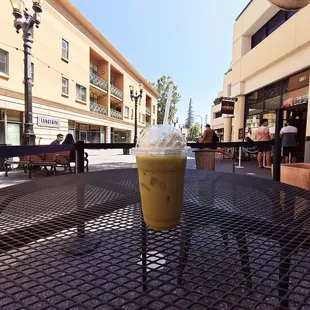 Iced matcha almond milk large and in charge. Plastic cup and metal table and business signage. :^&apos;0. Just kidding. Lol