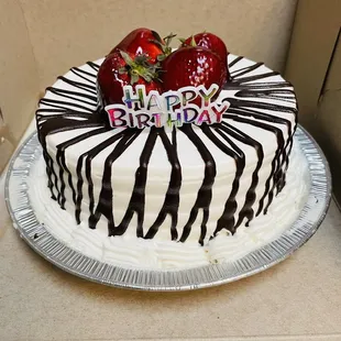 a birthday cake with chocolate drizzle and strawberries