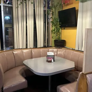 a corner booth with a table and chairs