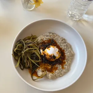 a bowl of oatmeal with sauce and vegetables