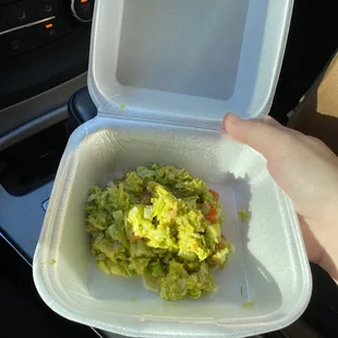 a hand holding a container of salad