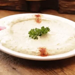 a plate of hummus with a sprig of parsley on top