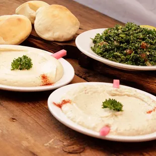 three plates of hummus and bread