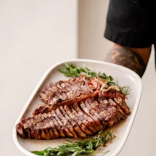 a person holding a plate of steak