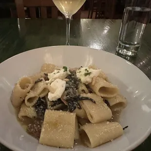 Assorted mushroom paccheri pasta with pine nuts and ricotta.