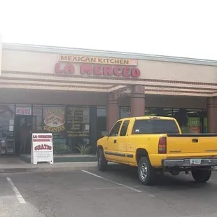 a yellow truck parked in front of a mexican restaurant