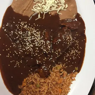 Mole poblano con arroz y frijoles refritos.