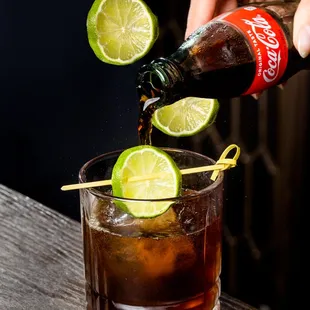 a person pouring a drink into a glass