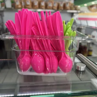 pink plastic spoons in a clear container