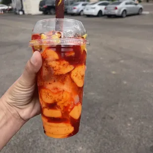 a hand holding a plastic cup with a drink in it