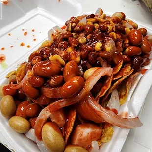 Tostilocos: cuernitas pickled porkstrips, Japanese peanuts, peanuts, jicama and cucumber, chamoy candy bits, doritos, sour spicy red sauce