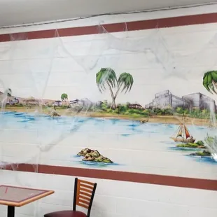 a table and chairs in front of a mural