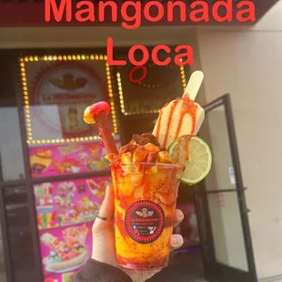 a hand holding a cup of mango ice cream