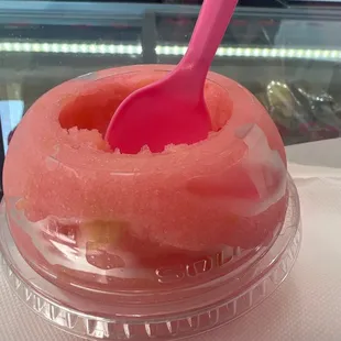 a pink spoon sticking out of a bowl of watermelon
