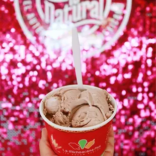 a hand holding a cup of ice cream