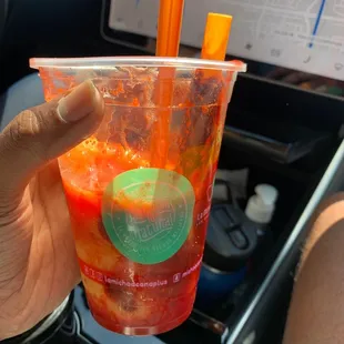 a hand holding a plastic cup with orange straws