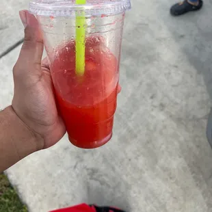 a hand holding a plastic cup with a straw