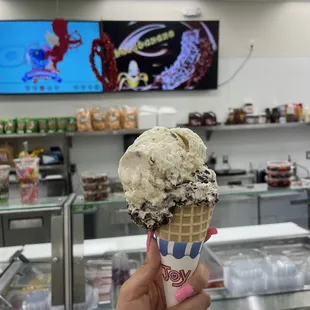 a hand holding a cone of ice cream