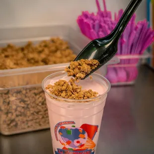 a plastic cup with a spoon full of granola
