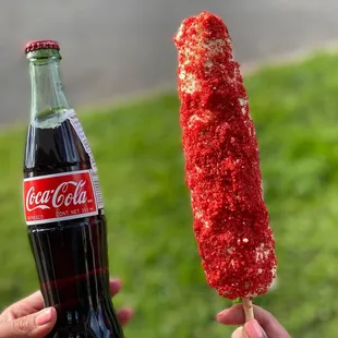 a hand holding a coke bottle and a long stick