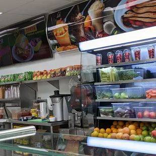 Behind the counter, fresh fruit and veggies, chips.
