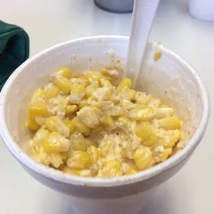 a bowl of corn with a spoon in it